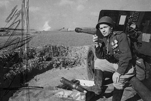Герой Советского Союза ефрейтор-артиллерист курит, сидя на станине пушки ЗИС-3